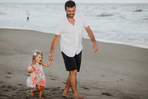 Apa boldogan sétál kislányával a tengerparton