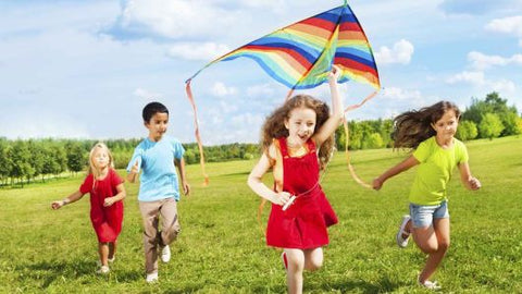 vidám gyerekek papírsárkányt eregetnek